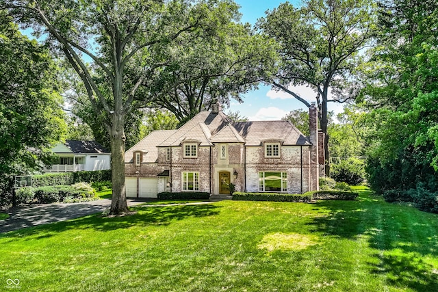 tudor house featuring a garage and a front lawn