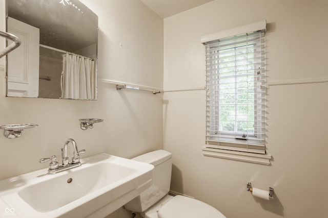 bathroom featuring walk in shower, a healthy amount of sunlight, toilet, and sink