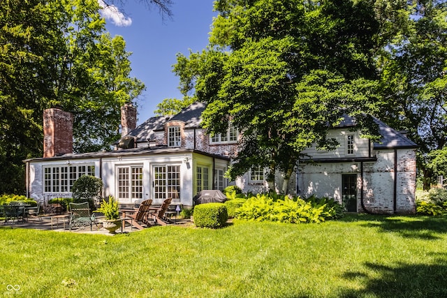 back of property with a patio, a lawn, and french doors