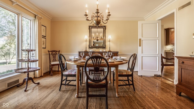 dining space with wood-type flooring, a notable chandelier, and crown molding