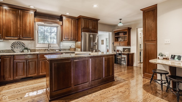 kitchen with sink, light stone countertops, and stainless steel refrigerator with ice dispenser