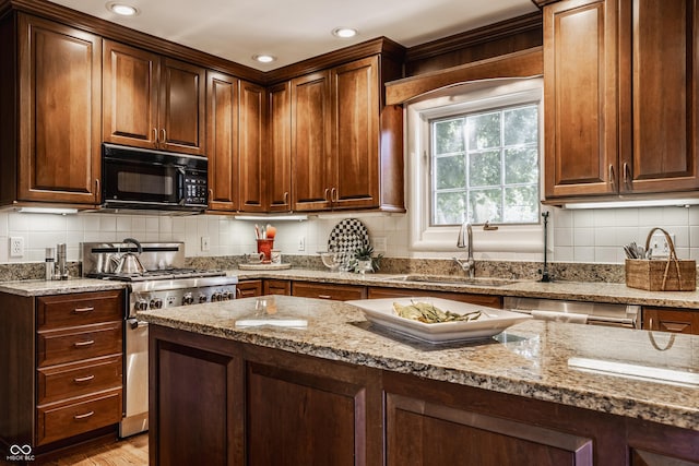 kitchen with stainless steel appliances, sink, light stone counters, and decorative backsplash