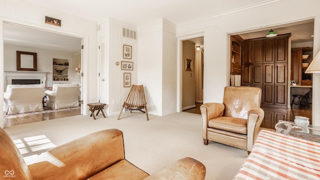 living room with crown molding, light colored carpet, and built in shelves