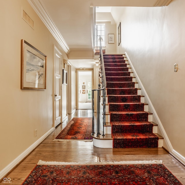 stairway featuring hardwood / wood-style floors and crown molding