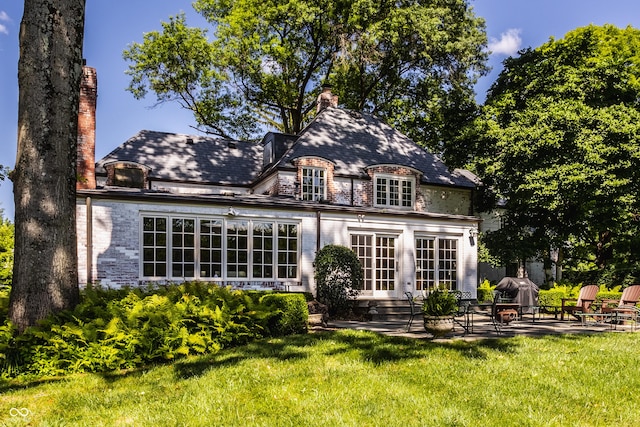 rear view of house with a lawn and a patio