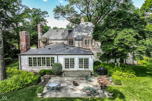 back of property with french doors, an outdoor fire pit, a patio area, and a lawn