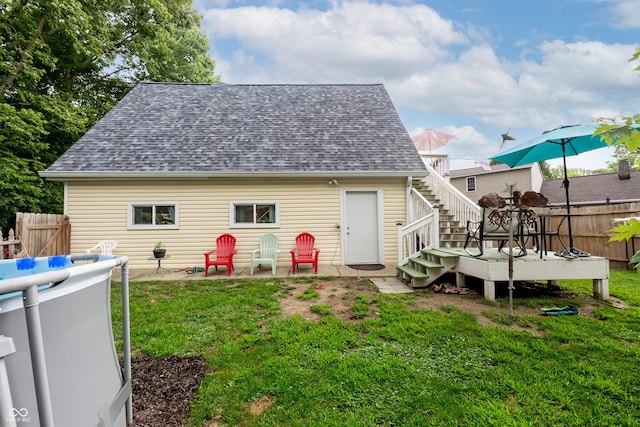 rear view of house with a patio, a lawn, and a wooden deck