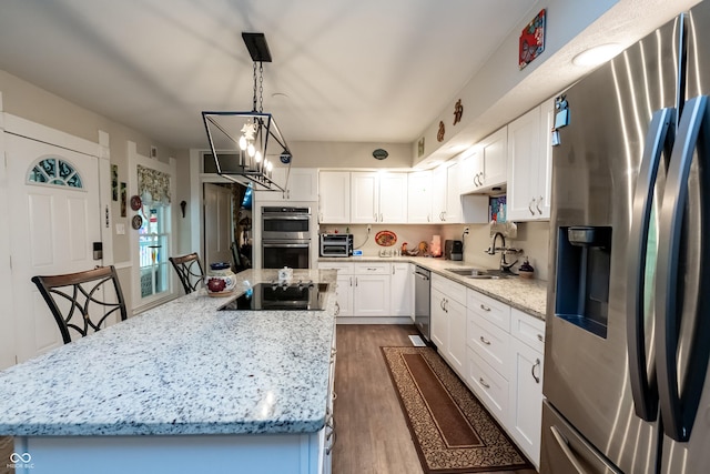 kitchen with white cabinetry, sink, light stone counters, a chandelier, and appliances with stainless steel finishes