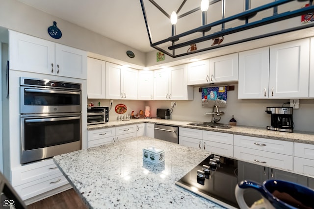 kitchen with light stone countertops, white cabinetry, sink, and stainless steel appliances