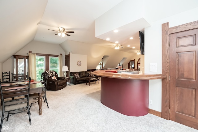 kitchen with kitchen peninsula, ceiling fan, light carpet, and vaulted ceiling