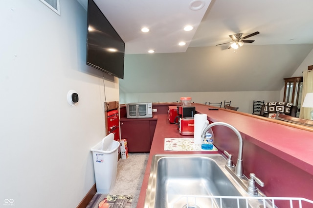 kitchen with ceiling fan, sink, carpet floors, and vaulted ceiling