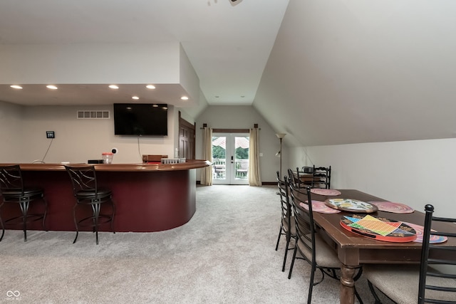 carpeted dining room featuring french doors and vaulted ceiling