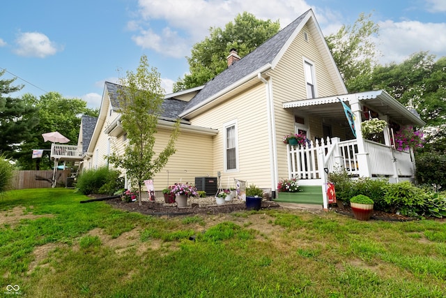 rear view of property featuring a porch, a yard, and central AC unit