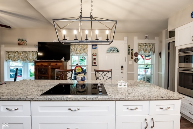 kitchen featuring light stone countertops, white cabinetry, hanging light fixtures, stainless steel double oven, and black electric cooktop