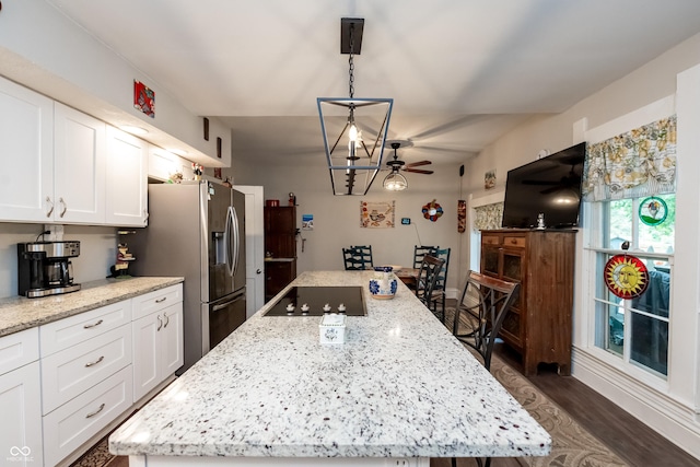 kitchen featuring black electric cooktop, ceiling fan, a center island, and white cabinets