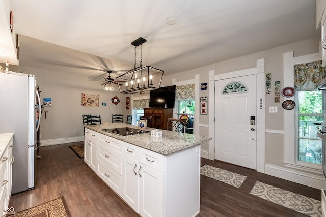 kitchen with stainless steel refrigerator, white cabinetry, light stone counters, black electric stovetop, and a kitchen island