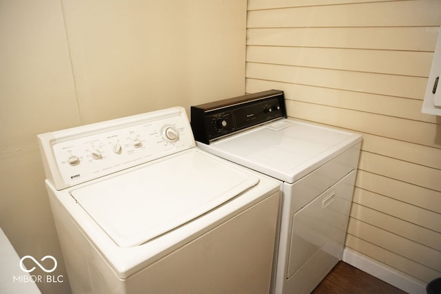 laundry room with washing machine and dryer and wood walls