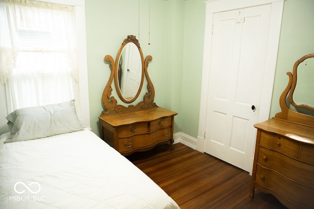 bedroom with dark hardwood / wood-style flooring and a closet