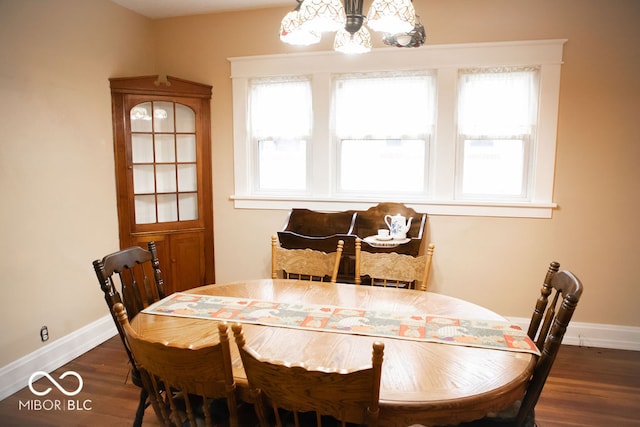 dining room with a wealth of natural light, dark wood-type flooring, and an inviting chandelier