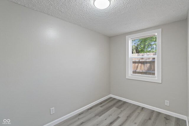 spare room featuring light hardwood / wood-style flooring and a textured ceiling