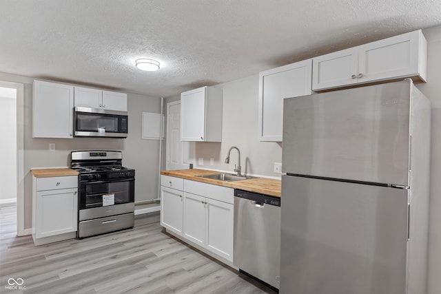 929 Olin Ave, Indianapolis, IN 46222 - kitchen featuring wood counters, sink, appliances with stainless steel finishes, light hardwood / wood-style floors, and white cabinets