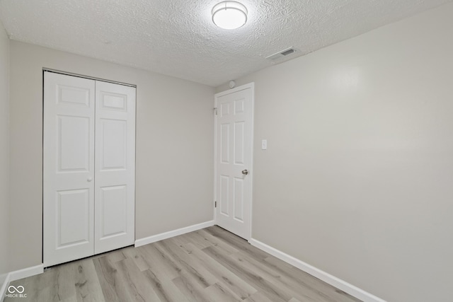 929 Olin Ave, Indianapolis, IN 46222 - unfurnished bedroom with a textured ceiling, light wood-type flooring, and a closet