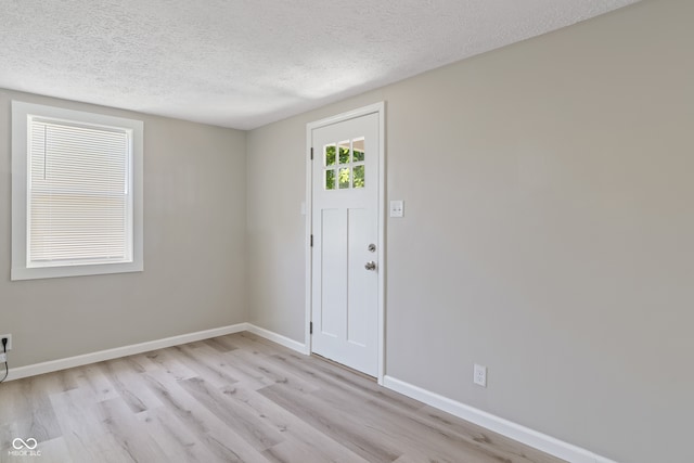 entryway with light hardwood / wood-style flooring and a textured ceiling