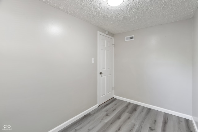 unfurnished room with a textured ceiling and light wood-type flooring