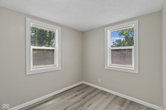 unfurnished room with light hardwood / wood-style floors and a textured ceiling