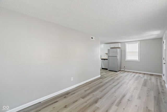 unfurnished living room featuring a textured ceiling and light wood-type flooring