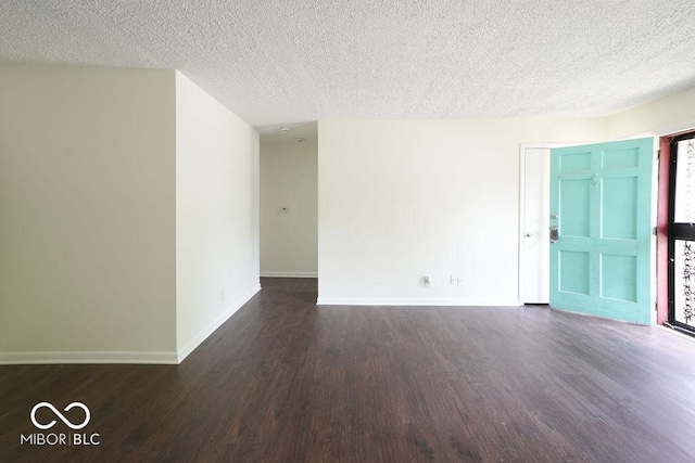 unfurnished room with dark wood-style floors, baseboards, and a textured ceiling