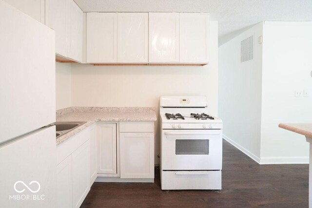 kitchen with sink, white cabinets, dark hardwood / wood-style floors, and white appliances