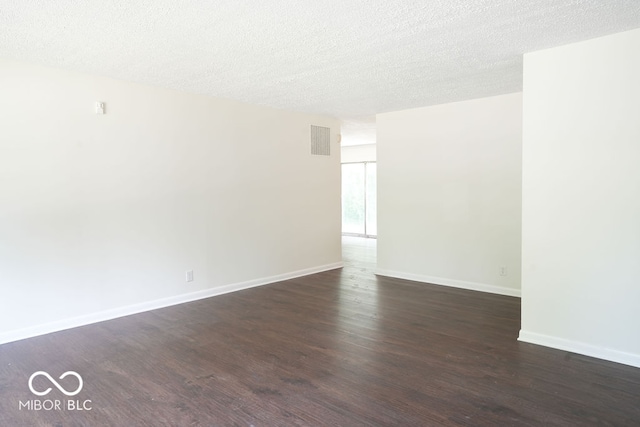 empty room with a textured ceiling and dark hardwood / wood-style flooring