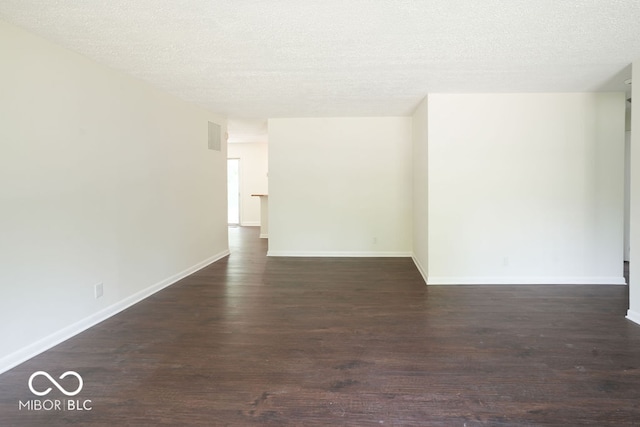 spare room with a textured ceiling and dark hardwood / wood-style flooring