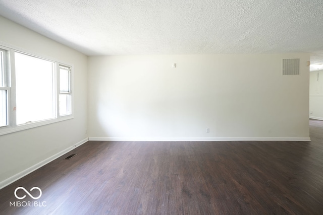 unfurnished room featuring a textured ceiling and dark hardwood / wood-style floors