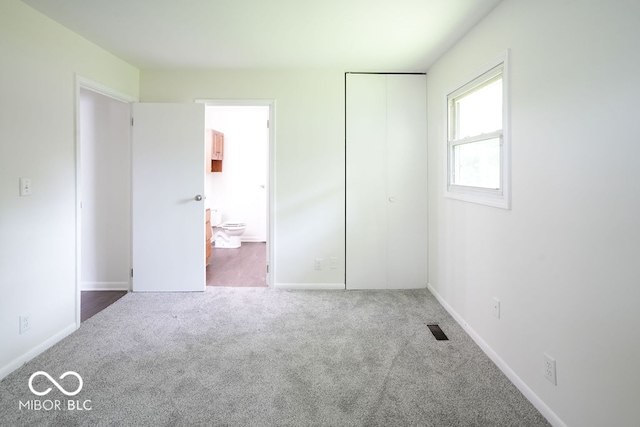 unfurnished bedroom featuring connected bathroom and carpet flooring