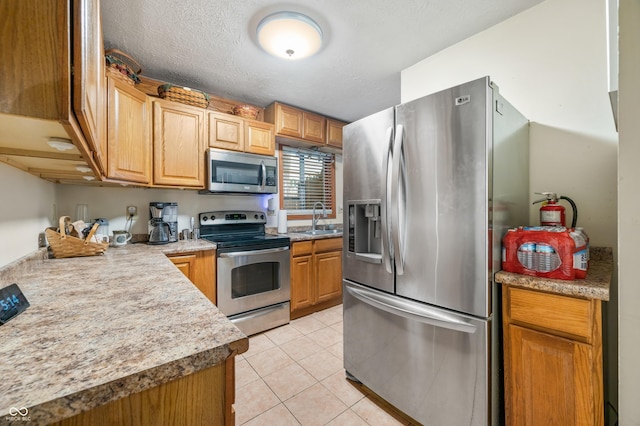 kitchen with stainless steel appliances, sink, a textured ceiling, and light tile patterned floors