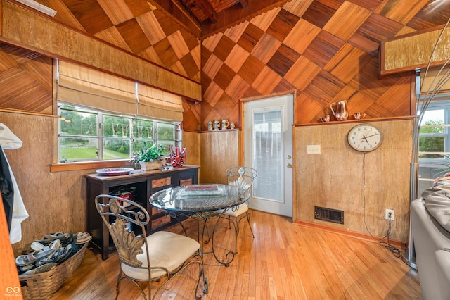 dining space with high vaulted ceiling, hardwood / wood-style flooring, wooden ceiling, and wood walls