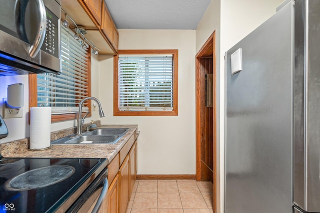 kitchen featuring sink, light tile patterned floors, a textured ceiling, and appliances with stainless steel finishes