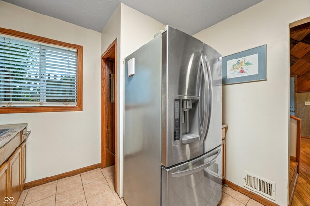 kitchen with stainless steel fridge with ice dispenser and light tile patterned flooring