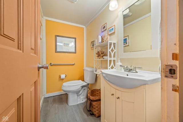 bathroom featuring hardwood / wood-style flooring, crown molding, vanity, and toilet