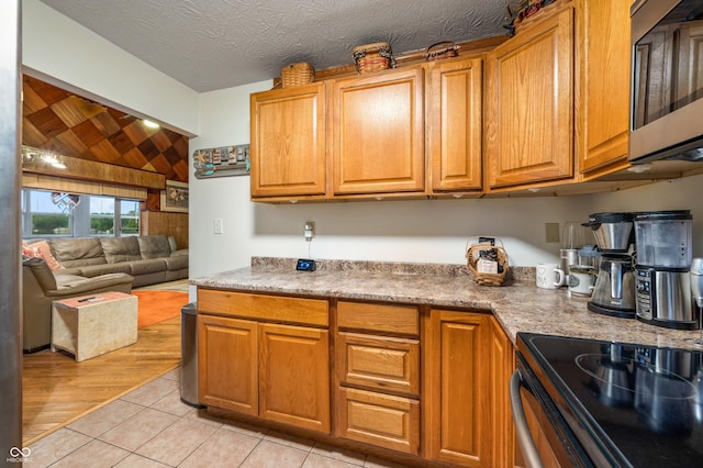 kitchen with electric range, a textured ceiling, and light tile patterned floors