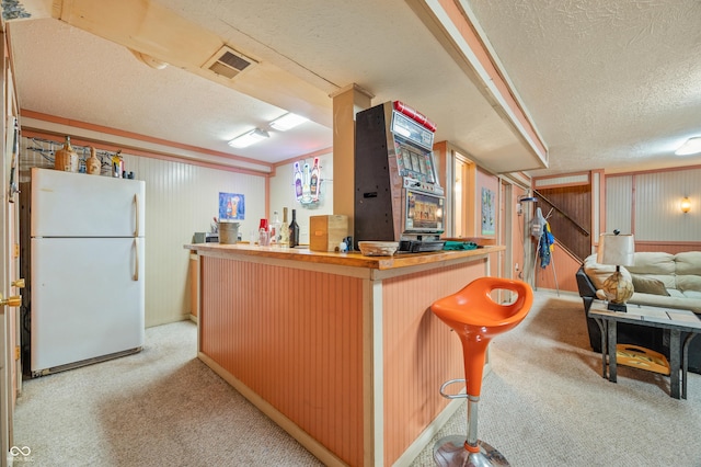 bar featuring white fridge, light carpet, and a textured ceiling