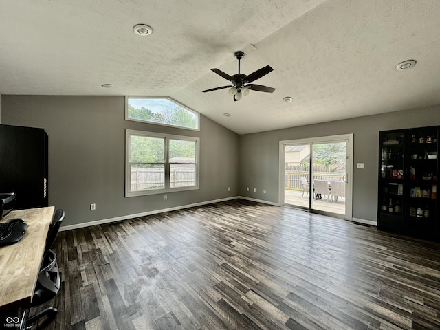 unfurnished living room with dark hardwood / wood-style flooring, vaulted ceiling, plenty of natural light, and ceiling fan