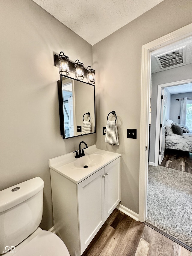 bathroom with vanity, wood-type flooring, a textured ceiling, and toilet