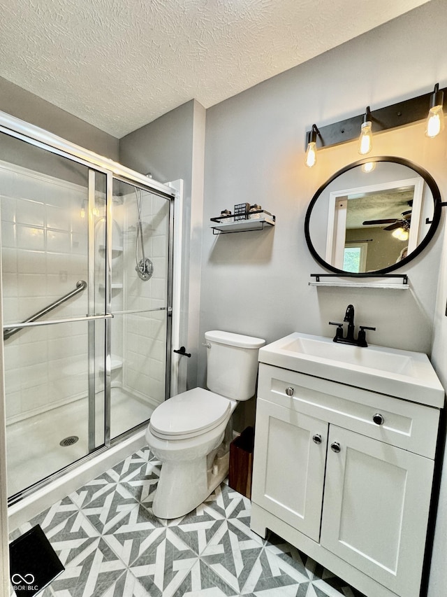 bathroom featuring vanity, an enclosed shower, a textured ceiling, and toilet