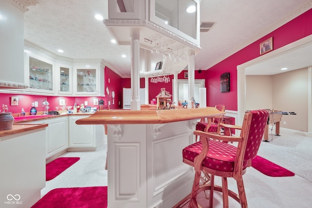 kitchen featuring a textured ceiling, white cabinetry, butcher block countertops, and light tile patterned floors