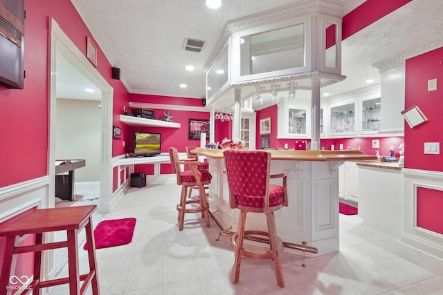 bar featuring white cabinets, light tile patterned floors, and a textured ceiling