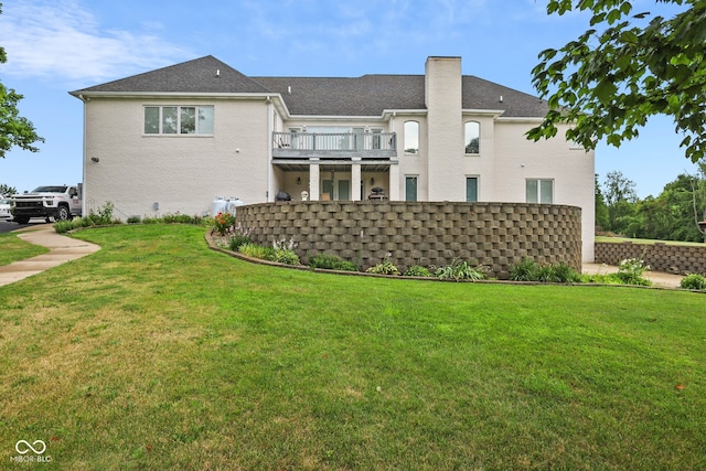 rear view of property featuring a balcony and a lawn