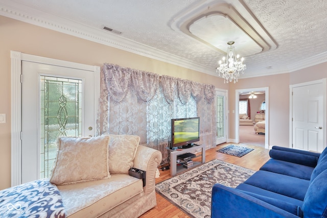 living room featuring ornamental molding, a textured ceiling, hardwood / wood-style flooring, and a wealth of natural light